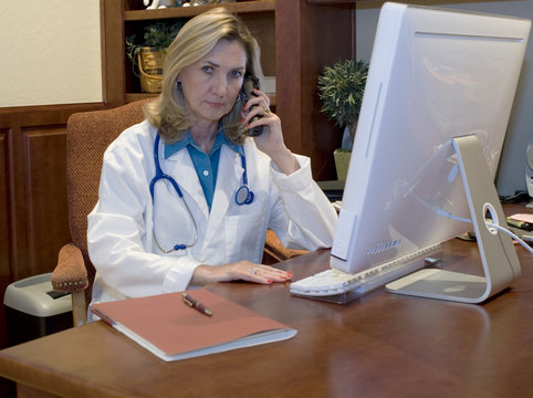 Female Doctor Talking On Phone In Her Office