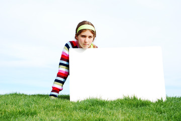 young girl is holding a blank board at outdoor location