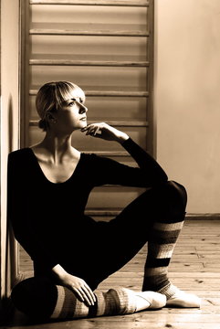 Beautiful ballet dancer sitting on a floor and relaxing after ex