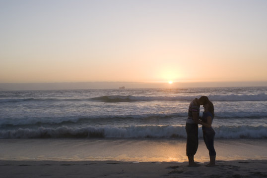 silhouetted couple kissing at sunset on a cape town beach