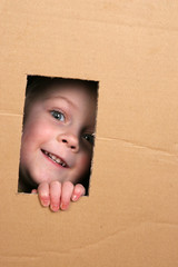 young girl looking from brown carton box