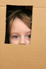 young girl looking from brown carton box