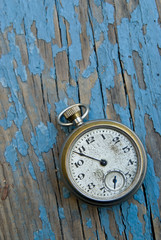 Antique pocket watch clock face on a peeling paint table