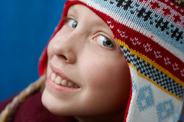 Young girl wearing woolen cap, scarf and gloves on blue