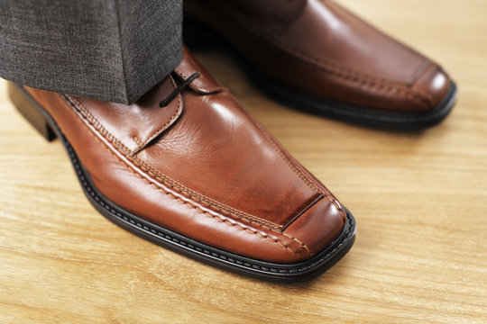 Feet with new brown leather shoes. Very short depth-of-field.