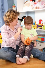 mother with child sit on floor in playroom