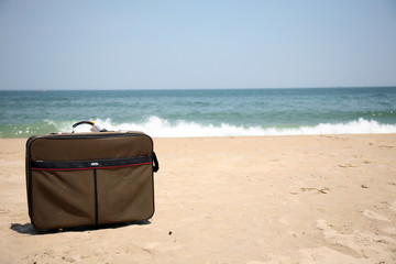 Conceptual shot of vacation travel with a suitcase on the beach