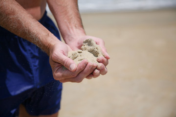 Man with a handful of sand on the beach