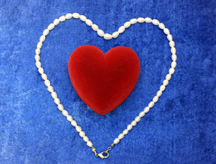 valentine day - red heart and pearly necklace on blue velvet