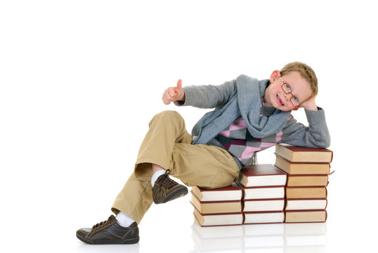Young boy, prodigy next to enclyclopedia books. 
