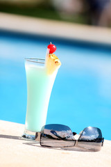 Cocktail und Sonnenbrille am Rand des Pools