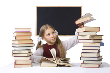 the pupil near a blackboard and piles of books
