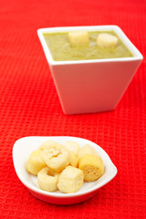 Bread croutons and spinach puree on red mat. Shallow DOF