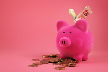 Piggy bank full of Money on a pink background