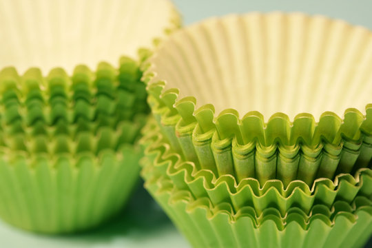 Close-up of green paper baking cups on a soft blue background