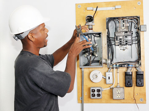 Electrician crimping a wire in an electrical panel.  