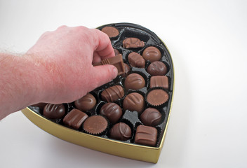Reaching in to a box of chocolate Valentine candy.