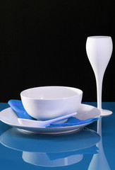 A contemporary dinning table set with plate, bowl and wine glass