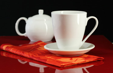 A coffee cup and teapot set on a red table