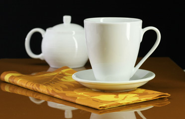 A coffee cup and teapot set on an orange table