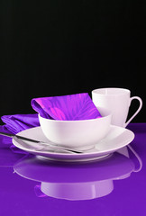 A modern table setting with white dishes on a purple background