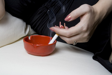 Obraz premium Woman smoking a cigarette on white sofa.
