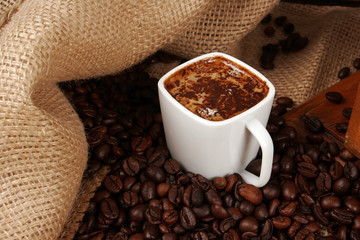 Coffee cup surrounded by coffee beans grains