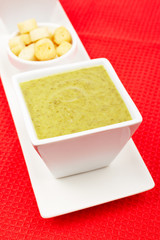 Spinach puree and bread croutons on red mat. Shallow DOF