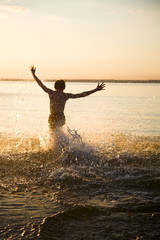 young happy man running on the evening beach