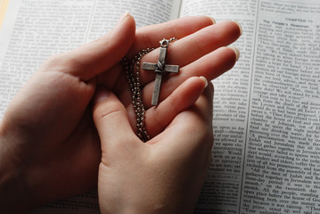 holy bible open with a cross on a hand