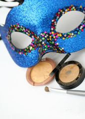 Golden eyeshadows with brush and blue carnival mask