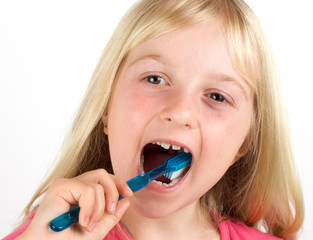 Girl brushing her teeth against white background
