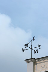weathervane at the corner of a building - obrazy, fototapety, plakaty