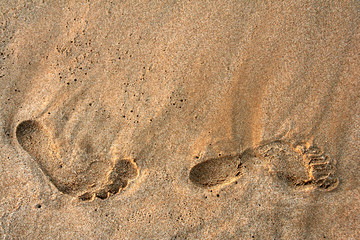 foot prints on the beach sand on sunrise