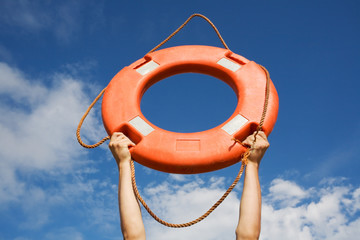 Life buoy ring in man's hands on a background of the sky.