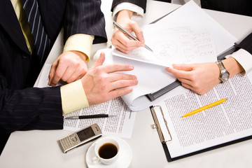 Business people’s hands on the table with a coffee and a cell 