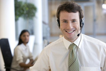 Businessman with headset and a woman colleague behind