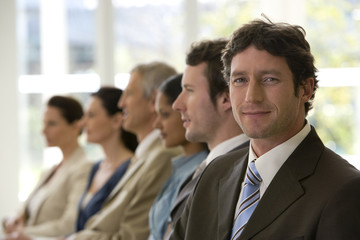Confident businessman with team seated in line with him