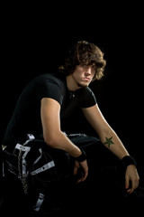 An alternative styled young man posing over black.