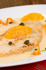 Closeup of grilled skate (ray) with ogange and caper sauce.