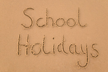 School Holidays handwritten in sand.