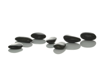 Seven black pebbles with reflections on a white background