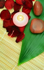 Spa composition of stones and red petals of rose with green leaf