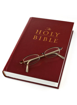 Open bible with folded reading glasses. Focus on glasses.