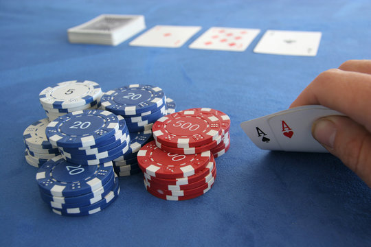 A poker player holds a pair of aces in his hands