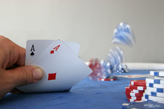 A poker player holds two aces and throws chips on the table