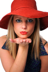 Beautiful young girl with red hat blowing a kiss