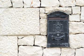 old and green mail box in a white stone wall