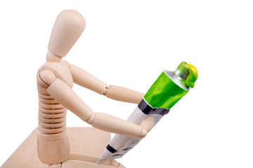 seated mannequin holding green painting tube isolated on white