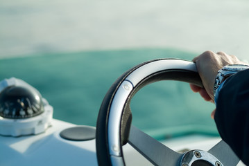 a hand with a steering wheel rudder - obrazy, fototapety, plakaty